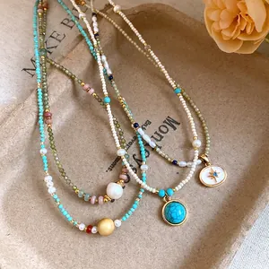 Detailed view of vintage stone beaded necklaces featuring pearls and gold pendants