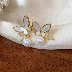 Close-up of 14k gold plated butterfly stud earrings with dangling pearls and zircons