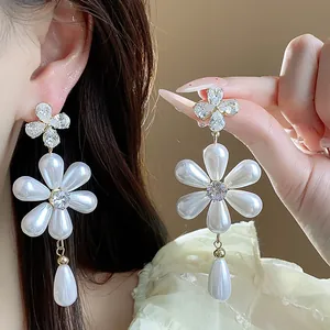 Close-up detail of silver needle flower earrings featuring white pearls and sparkling zircons
