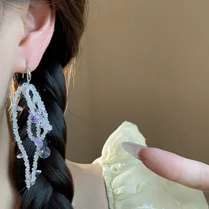 Macro detail of elegant glass beaded bow tassel earrings with purple crystal accents