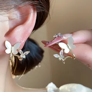 Macro detail shot of 14k gold plated butterfly earrings with zircon and shell wings