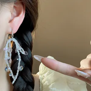 Close-up of elegant glass beaded tassel earrings worn on ear with pink crystal charms