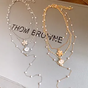 Detailed view of layered pearl necklaces featuring shell and flower charms in gold and silver
