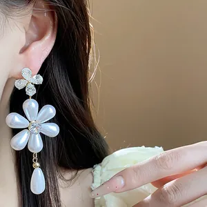 Close-up of elegant floral pearl drop earrings with zircon embellishments on model