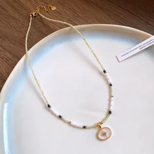 Detail of vintage beaded necklace with a gold starburst pendant on a ceramic plate.