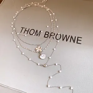 Detailed view of a multi-layered pearl necklace with shell and flower pendants.