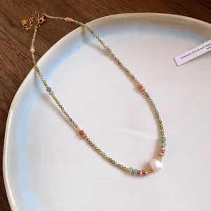 Close-up of vintage beaded necklace with colorful stones and a central white pearl