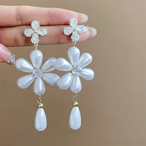 Close-up of elegant flower zircon stud earrings with white teardrop pearl pendants