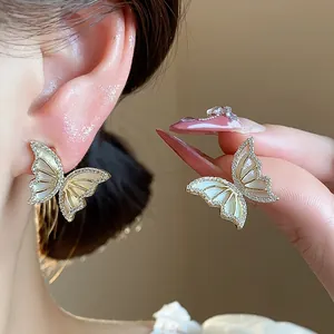 Close-up of 14k gold plated butterfly stud earrings with sparkling zircon and shell inlay