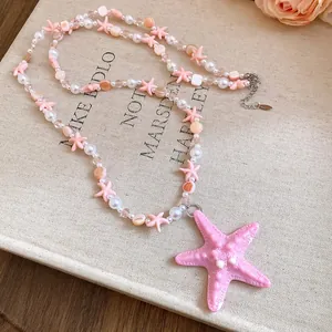 Dettaglio di una collana a due strati con perline e stelle marine rosa per le vacanze estive.