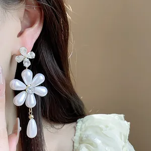 Elegant floral pearl earrings with sparkling zircon teardrop detail worn by model