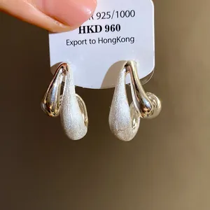 Dettaglio di orecchini a cerchio a goccia d'acqua placcati in oro 18k spazzolato
