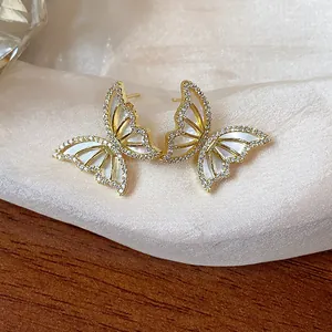 Detail view of 14k gold plated butterfly stud earrings with shell and sparkling zircon