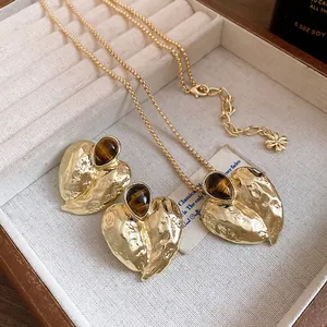 Detailansicht eines goldenen Herzanhängers mit Tigerauge-Stein und Metalltextur.