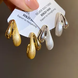 Primo piano macro di orecchini a goccia d'acqua placcati in oro 18 carati spazzolati