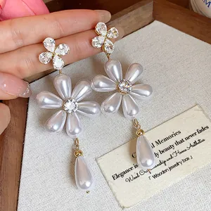 Close-up of elegant floral pearl drop earrings featuring crystal studs and teardrop pearls.