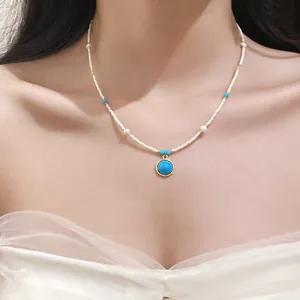 Close-up of a vintage stone beaded necklace with a blue round pendant on a model