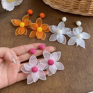 Close-up detail of bohemian hollow flower earrings with raffia woven centers for summer.