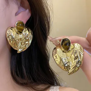 Nahaufnahme von goldenen Vintage-Herzohrringen mit edlen Tigerauge-Stein-Inlays.