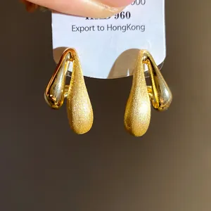 Dettaglio che mostra il contrasto tra finiture spazzolate e lucide su orecchini in oro 18k