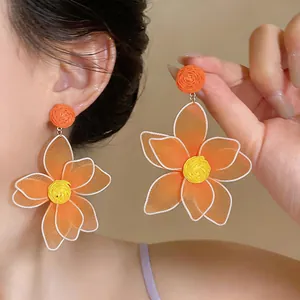 Detail shot of bohemian style orange 3D mesh flower earrings with intricate raffia texture