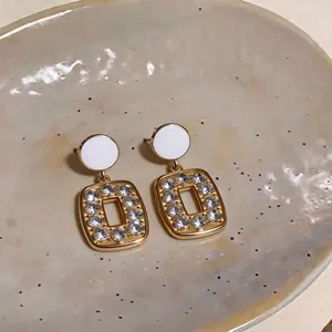 French retro square rhinestone earrings with white circular studs on a ceramic plate