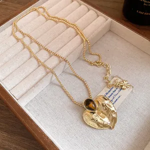 Detailansicht der goldenen Herz-Halskette mit Faltenstruktur und Tigerauge-Stein