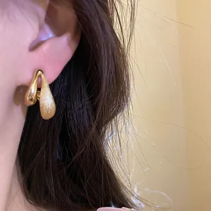 Dettaglio di orecchini a goccia placcati in oro 18k con finitura spazzolata