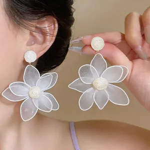 Close-up of white 3D mesh flower earrings with raffia woven center