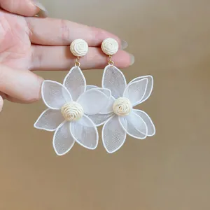 Detail of white mesh flower earrings with woven raffia center for bohemian beach style.