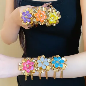Detailed view of colorful enamel flower bangles featuring a vintage gold finish and open cuff design
