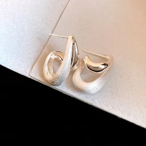 Dettaglio ravvicinato di orecchini a goccia in argento spazzolato con finitura opaca.