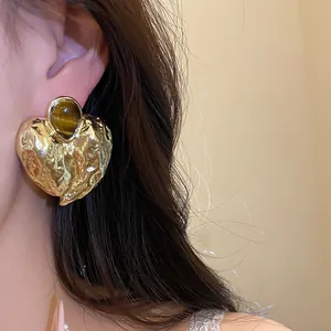 Detaillierte Nahaufnahme von Vintage-Herzohrringen mit Tigerauge-Stein am Modell