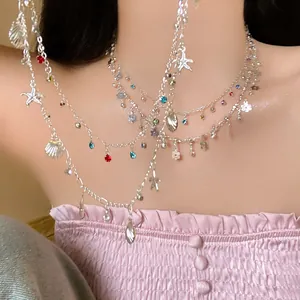 Detail of layered silver necklace with shell, starfish charms and colorful rhinestones