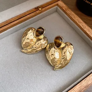 Nahaufnahme von Vintage-Herzohrringen aus Gold mit Tigerauge-Stein in einer Box.