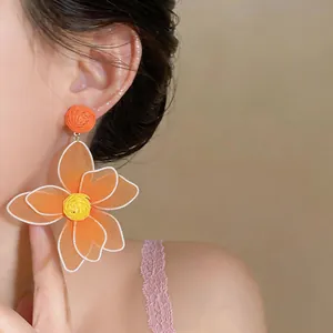 Detailed macro view showing large orange mesh flower earrings on an Asian model