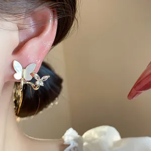 Detailed close-up showing gold butterfly wrap earrings with zircon and pearly finish on ear