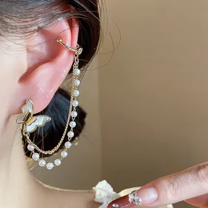 Close-up detail of 14k gold plated butterfly earrings with pearl chain and ear cuff.