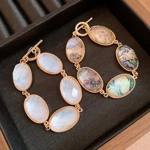 Close-up of elegant gold OT toggle bracelets with faceted white and abalone resin inserts
