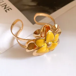 Detailed view of a vintage gold metal cuff bracelet with yellow enamel flower petals.