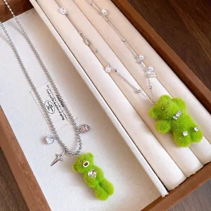 Close-up of cute green plush bear necklaces with pearls and zircons in a jewelry box