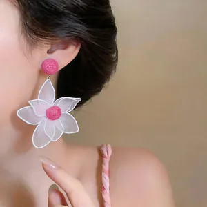 Close-up detail of white hollow mesh floral earrings with rose pink center on model