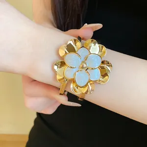Detail of vintage gold-toned double-layer flower open cuff bangle on female model wrist