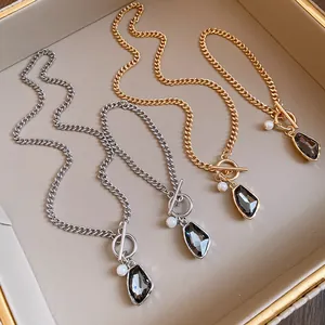 Detailed view showing gold and silver chain necklaces with grey crystal pendants and pearls.