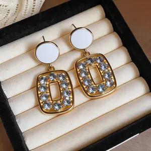 Close-up of vintage gold-tone earrings with white circular studs and blue crystal frames