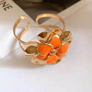 Detailed view of elegant gold-plated cuff bangle with orange enamel double-layered flower