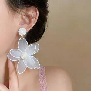 Detailed view of white floral drop earring with intricate mesh petals