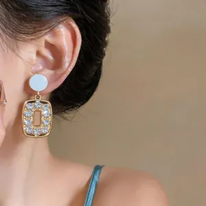 Detailed close-up of vintage French gold-tone earrings with white studs and rhinestones