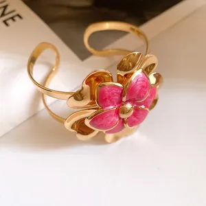 Close-up of a vintage gold cuff bracelet with a pink enamel double-layer flower.