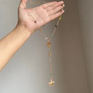 Dettaglio della collana a Y dorata con perle di pietra colorate e ciondoli a conchiglia